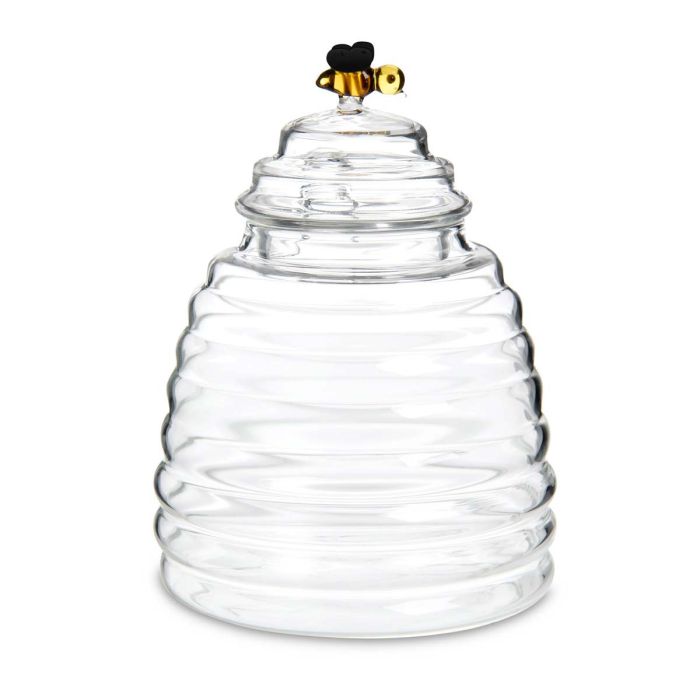 Clear glass beehive-shaped container with a bee on top against a white background